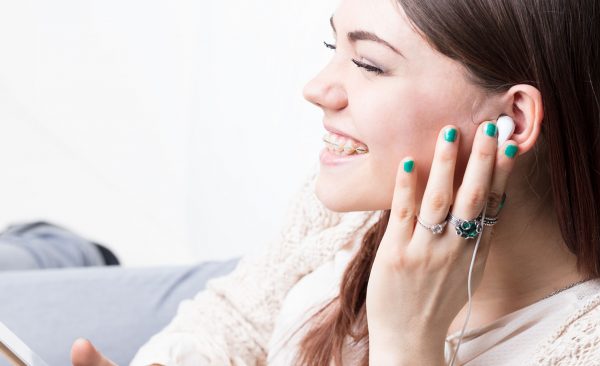 young woman enjoying music with her smartphone in on a sofa in her living room